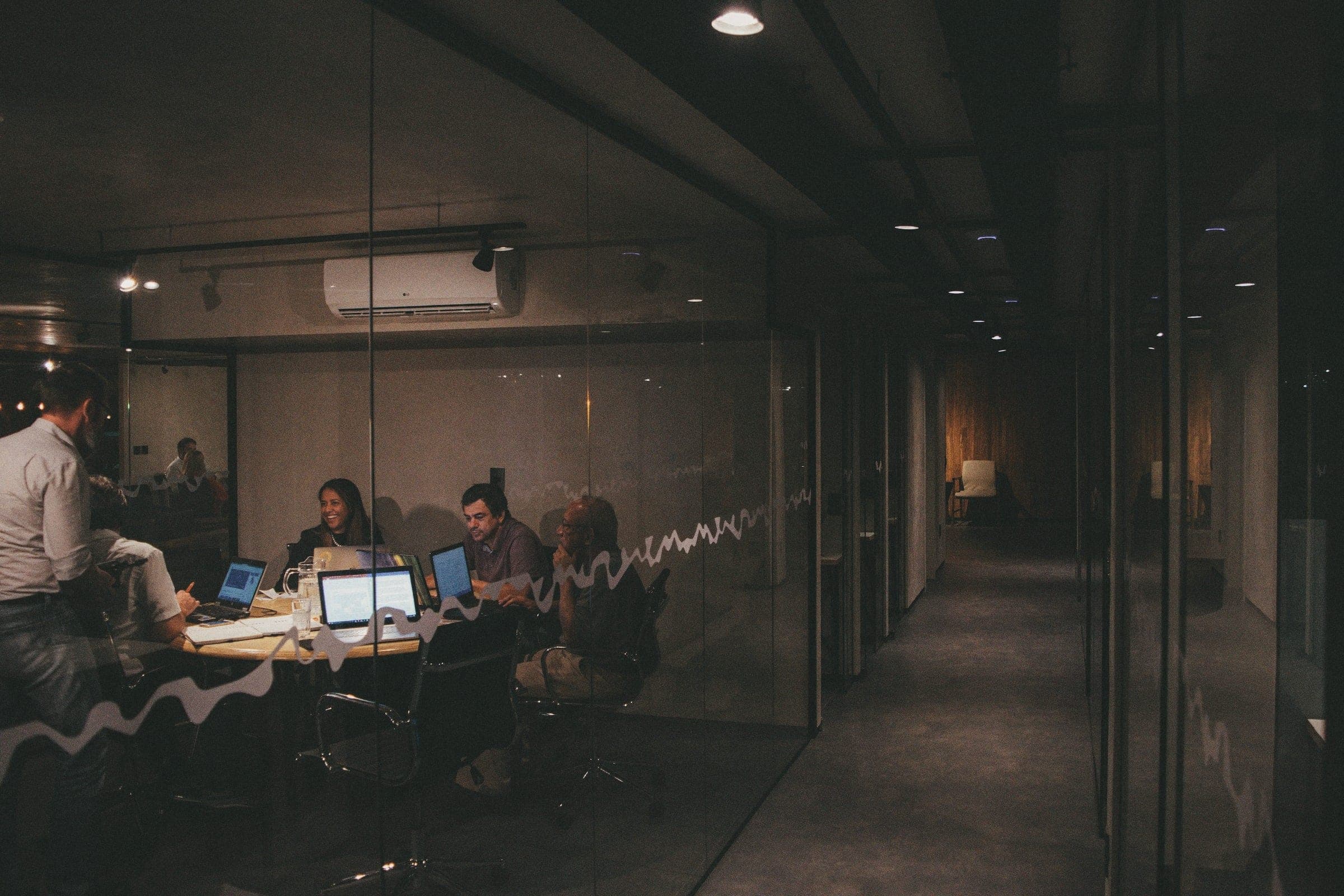 A team working late in a dim glass-walled office
